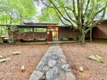 Stunning exterior view of a mid-century modern home with a stone pathway and wooded surroundings at 808 Indian Springs Rd, Chapel Hill, NC 27514