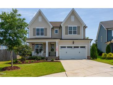 Charming two-story home with a well-manicured lawn, inviting porch, and a two-car garage at 857 Mill Station Ln, Wendell, NC 27591