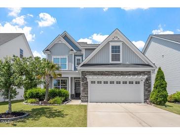 Charming two-story home with a two car garage, stone accents, manicured lawn, and mature landscaping at 1161 Tulip Poplar Rd, Fuquay Varina, NC 27526