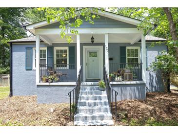 Charming home featuring a cozy front porch with seating and beautiful gray exterior with teal shutters at 120 Pine St, Carrboro, NC 27510