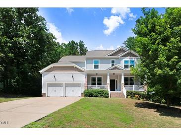 Charming two-story home with a covered front porch, a two-car garage, and a well-manicured lawn at 1304 Double Oak Ln, Willow Springs, NC 27592