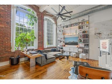 Inviting living room with exposed brick, large windows, and a stylish shelving unit at 1535 Caraleigh Mills Ct # 210, Raleigh, NC 27603