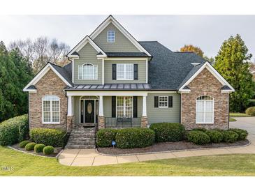 Charming home featuring a stone and siding facade, inviting front porch, and well-manicured lawn at 2100 Stone Pasture Rd, Fuquay Varina, NC 27526