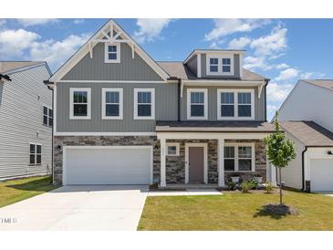 Charming two-story home with a stone facade, attached garage, and manicured lawn at 311 Horseshoe Pl, Angier, NC 27501