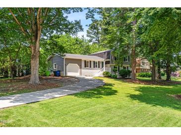 Charming two-story home features a well-manicured lawn, lush trees, and a long driveway leading to a garage at 4001 Pin Oak Rd, Raleigh, NC 27604
