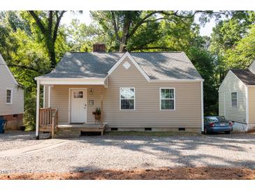 Charming, tan one-story home with gray roof, white trim and front porch surrounded by mature trees and gravel landscaping at 522 E Club Blvd, Durham, NC 27704