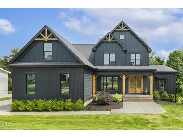 Stunning modern farmhouse with dark siding, gabled roofs, and manicured lawn at 1141 Duke Farm Dr, Wake Forest, NC 27587