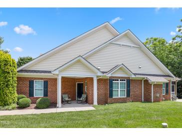 Charming brick home featuring a cozy front porch and well-maintained landscaping under a clear blue sky at 127 Bobwhite Way, Mebane, NC 27302