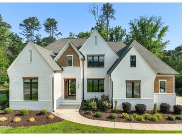 Charming two-story home featuring white brick, black framed windows, manicured landscaping, and a concrete walkway at 1409 Montvale Ridge Dr, Cary, NC 27519