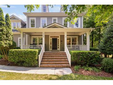 Inviting two-story home boasts a charming front porch, brick stairs and meticulously manicured landscaping at 228 Grantwood Dr, Holly Springs, NC 27540