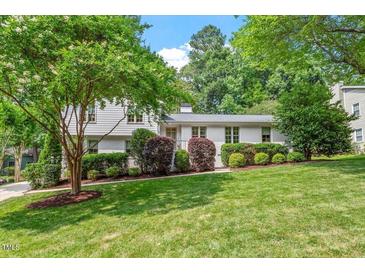 Charming two-story home with a lush green lawn, mature trees, and well-manicured shrubs at 3308 Cobblestone Court Ct, Raleigh, NC 27607