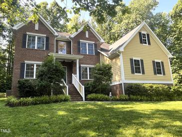Charming two-story home featuring brick and yellow siding with black shutters, surrounded by lush greenery at 3650 Pleasants Ridge Dr, Wake Forest, NC 27587