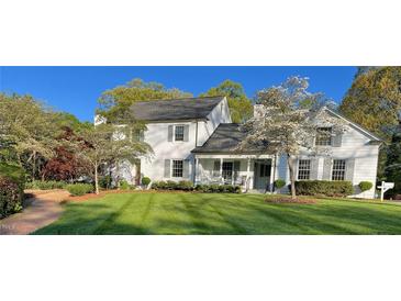 Charming two-story home featuring a well-manicured lawn, mature trees, and a welcoming front porch at 1004 E Willowbrook Dr, Burlington, NC 27215