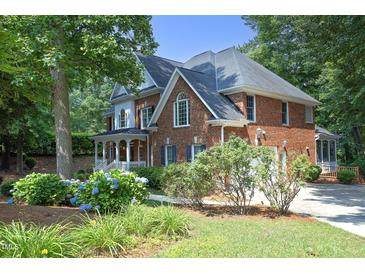 Beautiful two-story brick home with manicured lawn and lush landscaping in a serene, wooded setting at 101 Royal Glen Dr, Cary, NC 27518