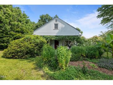 Charming home with abundant greenery and foliage covering the front exterior, offering a serene curb appeal at 1090 S Fifth St, Mebane, NC 27302