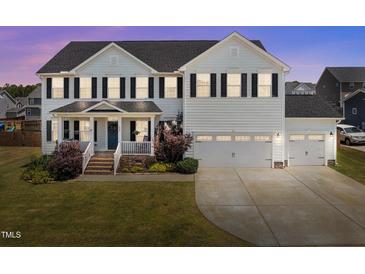 Beautiful two-story home with a well-maintained lawn, black shutters, and three-car garage at 204 Ashland Hill Dr, Holly Springs, NC 27540