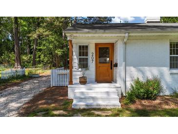 Charming front porch with wooden door and white painted brick on a sunny day at 207 N Aiken St, Fuquay Varina, NC 27526