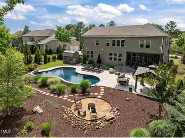This backyard oasis has a pool, cabana, outdoor seating, and a fire pit, perfect for entertaining at 814 Covered Bridge Trl, Chapel Hill, NC 27517