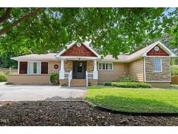 Charming single-story home with a unique facade, decorative trim, and lush greenery at 821 Woodburn Rd, Raleigh, NC 27605