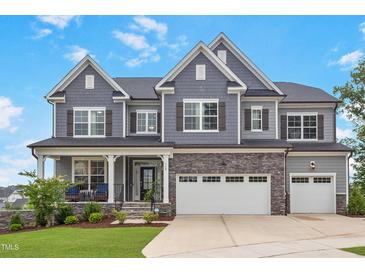Charming two-story home features a stone facade, gray siding, and a well-manicured lawn at 112 Bellmont Crest Dr, Holly Springs, NC 27540
