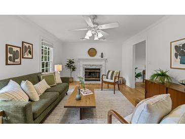 Bright living room featuring a fireplace, ceiling fan, wood floors, and stylish decor at 15 Gray Fox Ct, Durham, NC 27713