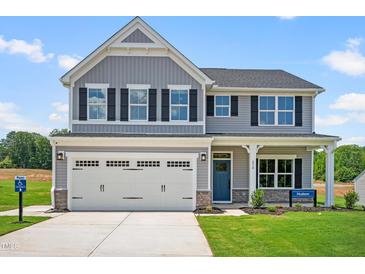 Charming two-story home with gray siding, black shutters, a blue front door, and well-manicured lawn at 210 Bluebell St, Sanford, NC 27330