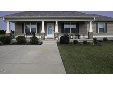 Charming home featuring a covered front porch with inviting rocking chairs and beautifully landscaped front yard at 60 Falling Leaf Ln, Benson, NC 27504