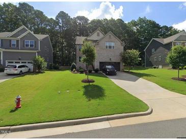 Charming brick two-story home with a well-maintained lawn and a long driveway at 8132 Wheeler Woods Dr, Apex, NC 27539