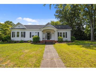 Charming one-story home with a well-manicured lawn, inviting front porch, and classic architectural details at 1000 College St, Oxford, NC 27565