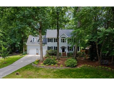 Charming two-story home featuring a manicured lawn, mature trees, and a two-car garage at 102 Turnberry Ln, Cary, NC 27518