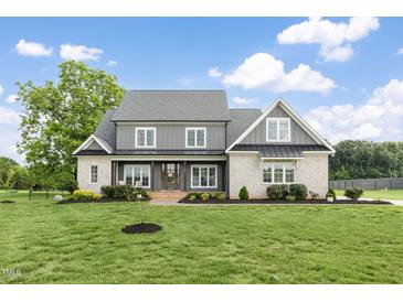 Stunning two-story home featuring a brick facade and beautiful manicured lawn and professional landscaping at 106 Garrison Farm Rd, Mebane, NC 27302