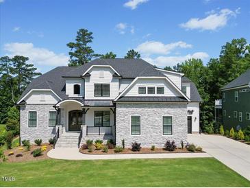 Beautiful two-story home featuring a stone and white facade, manicured lawn, and black window trim at 111 Stone Park Dr, Wake Forest, NC 27587