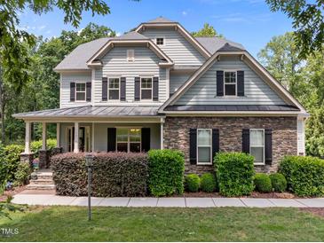 Charming two-story home with stone accents, black shutters, covered porch, and well-maintained landscaping at 12216 Kyle Abbey Ln, Raleigh, NC 27613