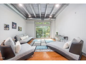 Bright living room with hardwood floors, modern furniture, and a sliding glass door to a balcony at 1300 St Marys St # 408, Raleigh, NC 27605