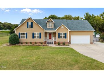 Charming tan house featuring blue shutters, a well-manicured lawn, and an attached two-car garage at 191 Bridle Dr, Angier, NC 27501