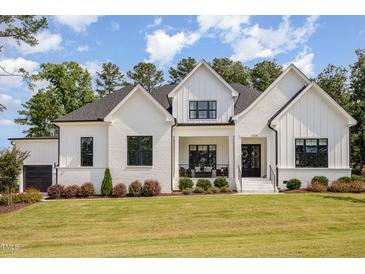 Charming new construction home featuring a modern farmhouse design, white brick, black trim, and a lush front yard at 2328 Sanctuary Dr, Raleigh, NC 27606