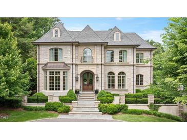 Elegant stone-clad home with manicured landscaping, arched windows, and a welcoming front entrance at 3347 Alamance Dr, Raleigh, NC 27609