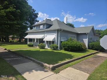 Classic two-story home features a covered front porch, green lawn and mature landscaping at 500 W Main St, Benson, NC 27504