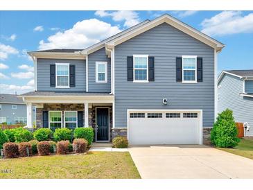 Charming two-story home with blue siding, a front porch, a two-car garage and well-maintained landscaping at 512 Teal Lake Dr, Holly Springs, NC 27540