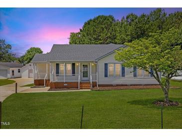 Charming single-story home featuring a well-manicured lawn, quaint front porch, and a detached garage at 5328 Trackway Dr, Knightdale, NC 27545
