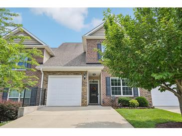 Charming brick townhome featuring a stone accent, black shutters, a white garage door, and a manicured lawn at 1004 Lake Michael Way, Mebane, NC 27302