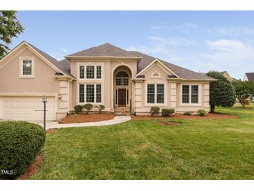 Elegant stucco home featuring manicured lawn, arched entryway, and bright, large windows at 101 Deerwalk Ct, Cary, NC 27513