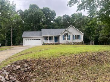 Charming single-story home featuring a blue front door, gray siding, and an attached two-car garage at 125 Tast Dr, Wendell, NC 27591