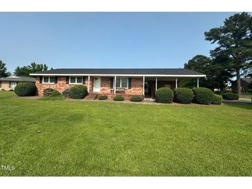Charming one-story brick home with well-maintained lawn, trimmed shrubs, and a covered carport at 202 Camelia Dr, Princeton, NC 27569