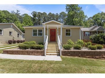 Charming single-story home with a red front door, white railings, brick foundation trim, and a well-manicured lawn at 2710 Broad St, Durham, NC 27704