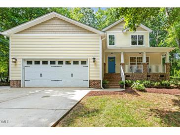 Charming yellow two-story home featuring a spacious garage, inviting porch, and well-manicured lawn at 2721 Rustic Brick Rd, Raleigh, NC 27603