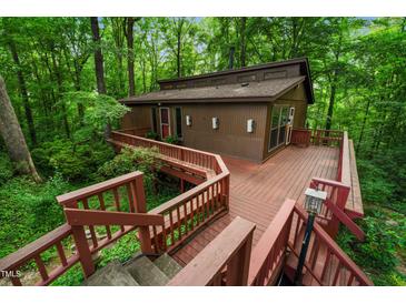 Secluded brown two-story home featuring an expansive wooden deck and lush, mature trees surrounding the property at 3416 Ocotea St, Raleigh, NC 27607