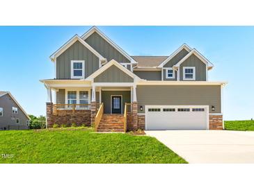 Inviting two-story home featuring a stone-accented porch and a two-car garage, set against a bright blue sky at 4896 Grosbeak Ct, Mebane, NC 27302