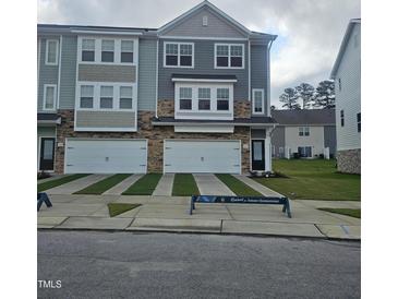 Modern townhome with a two-car garage, stone accents, and manicured lawn at 5330 River Reach Dr, Raleigh, NC 27616