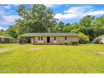 Charming single story brick home featuring a well-manicured lawn and mature trees at 605 Sexton Ave, Zebulon, NC 27597